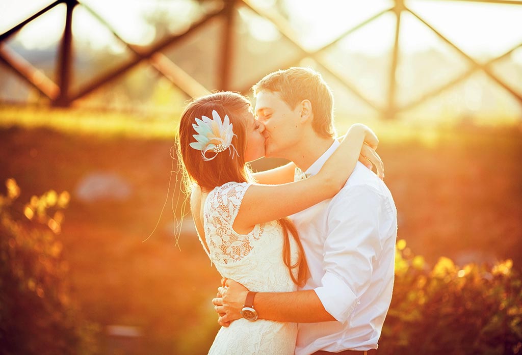 Newlywedded couple kissing in golden hour